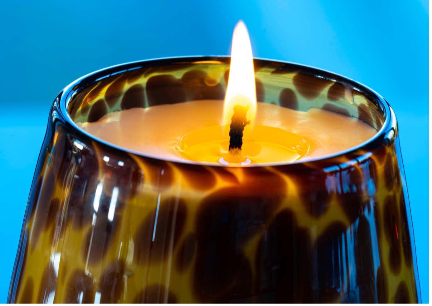 Close-up image of an animal print Renee candle with a lit flame.